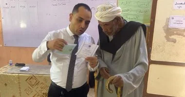 قاضٍ يساعد مسنًا للإدلاء بصوته داخل لجنة في أسوان
